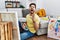 Young man with beard painting canvas at home crazy and mad shouting and yelling with aggressive expression and arms raised