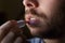 Young man with a beard repairing his damaged lips with moisturizer