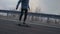 Young man with a beard riding skateboard cruising downhill on countryside road