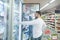 A young man with a beard takes frozen foods from a refrigerator in a supermarket. Shopping in the store