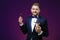 Young man with beard in tuxedo holds makeup brush and smiling on