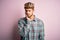 Young man with beard wearing golden crown of king standing over isolated pink background thinking looking tired and bored with