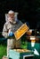 A young man beekeeper works on a beehive near the hives. Natural honey directly from the hive.