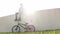 Young man with bicycle on green grass sitting in back light listening to music