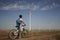 A young man on a bicycle rides past a wind power plant