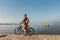 Young Man With Bicycle Walking On Coast And enjoying View Of Sea. Holiday Travel Activity Concept