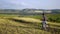 A young man on a bike rides along the fields at sunset, stops, looks around and rides on