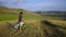 A young man on a bike rides along the fields at sunset, stops, looks around and rides on