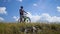 A young man on a bike stops on the rocky edge of the hill and looks around