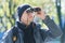 Young man with binoculars bird watching at demi-season natural background