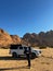 Young man with binoculars and car in desert. SUV off road auto vehicle.