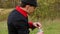 Young man in a black hat stands in a forest and drinks some liquid in slo-mo