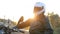 A young man in black leather jacket sits on motorcycle prepares his white helmet before journey at autumn sunset