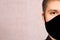 A young man in a black mask on a light background. necessary protection from covid-19. fabric reusable mask the guy does not have