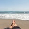 Young man in black shorts relaxes on the shore of the blue sea. Guy is resting lying on the sand enjoying the sea