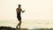 young man in a black sports suit is boxing against the backdrop of the sea