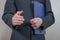 A young man in a black suit with a folder holds out his hand for a handshake. Business proposal