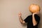 Young man in black t-shirt holding big pumpkin in front of his face