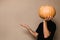 Young man in black t-shirt holding big pumpkin in front of his face