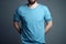 Young man in blank blue t-shirt on grey background. Mock up Ai generative