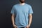 Young man in blank blue t-shirt on grey background. Mock up Ai generative