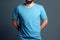 Young man in blank blue t-shirt on grey background. Mock up Ai generative