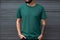 Young man with blank green t-shirt standing on street Mock up Ai generative