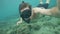 Young man blowing snorkeling mask for equalize pressure in ears while diving in sea. Man shooting selfie video while
