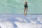 Young man in blue shorts swimming in the ocean under the blue sky