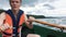 A young man in a boat rowing wooden oars on the water. Life jacket on the body of a man.