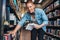 Young man at bookshelf at public library