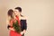 Young man with bouquet of flowers hugging his girlfriend on color background