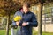 Young man with bouquet of spring flowers looks at wrist watch, urban background, man waiting his girlfriend