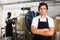 Young man brewer in uniform is standing in brew-house