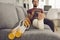 Young man with broken leg in cast sitting on couch with crutches and using tablet