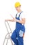 Young man builder in blue coveralls with screwdriver on ladder i