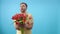 Young man with bunch of red tulips poses for the camera on blue background