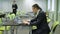 Young man in business suit with expensive wristwatch is working with the laptop sitting on green chair behind black desk