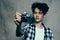 young man with a camera in hand and in a plaid t-shirt on a gray background indoors photographer