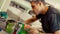 Young man in carpentry workshop fixing wheel on his skateboard