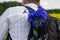 A young man carries a bouquet of cornflowers in a backpack behind his back.