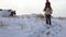 A young man carries a child in his arms on a snow-covered hill a blizzard begins