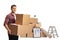 Young man carrying cardboard boxes and a pile of boxes packed for removal