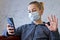 Young man in casual conversation over video call on cellphone in protective mask due to spread of coronavirus epidemic