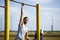 A young man of Caucasian appearance pulls himself up on a horizontal bar.