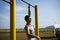 A young man of Caucasian appearance pulls himself up on a horizontal bar.