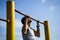 A young man of Caucasian appearance pulls himself up on a horizontal bar.