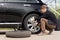 Young man changing the punctured tyre on his car