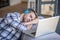 Young man in a checkered shirt sleeping on his laptop