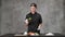 Young man chef cook in black clothes on a gray background. Kitchen table, ingredients for Japanese sushi and rolls.